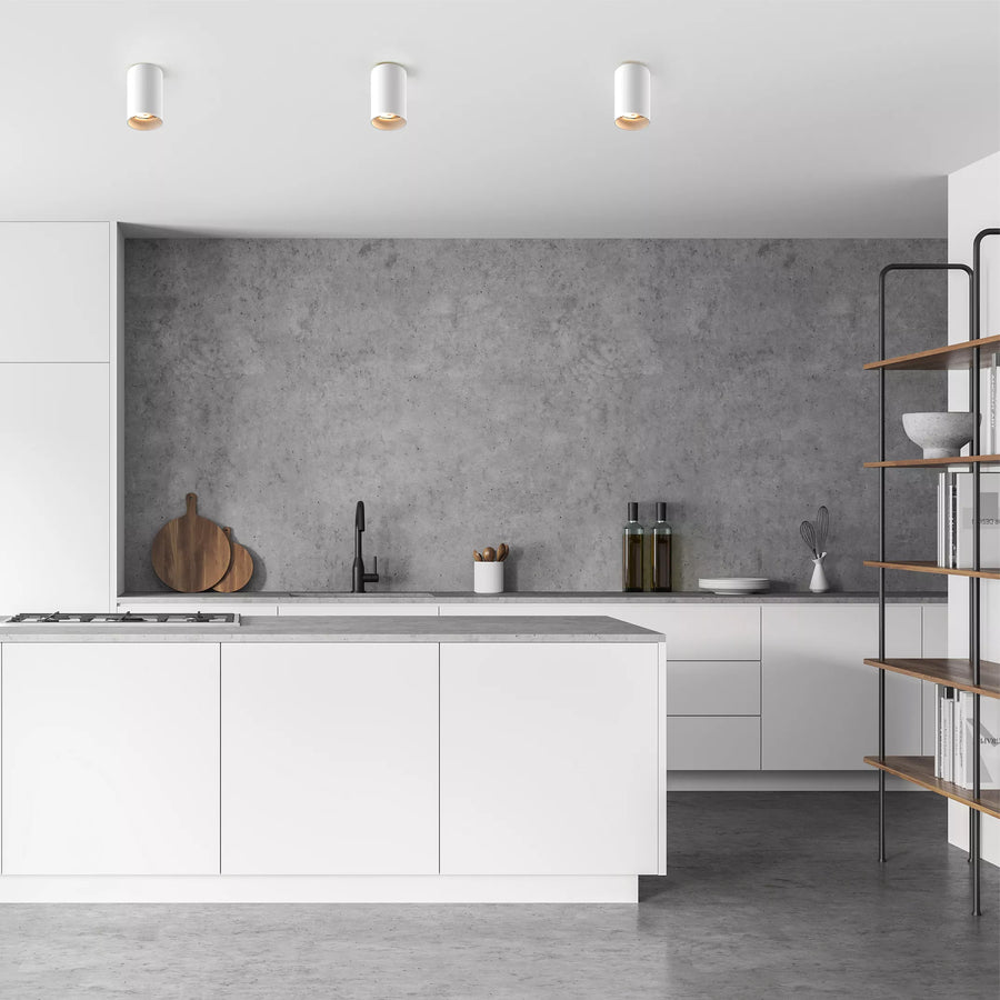 Trois spots blancs fixés au plafond dans une cuisine moderne minimaliste éclairée.