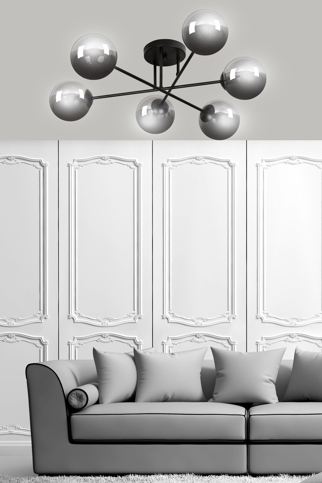 Mise en ambiance dans un salon, suspension devant murs moulurés blancs et canapé.