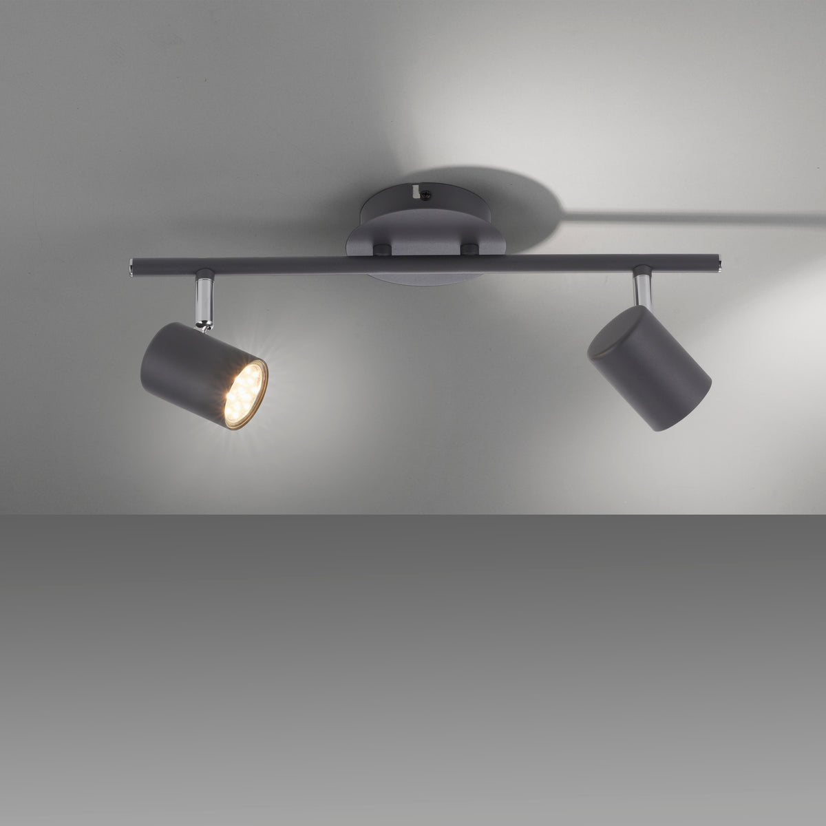 Spot allumé en situation, ombres portées sur plafond gris, lumière chaude