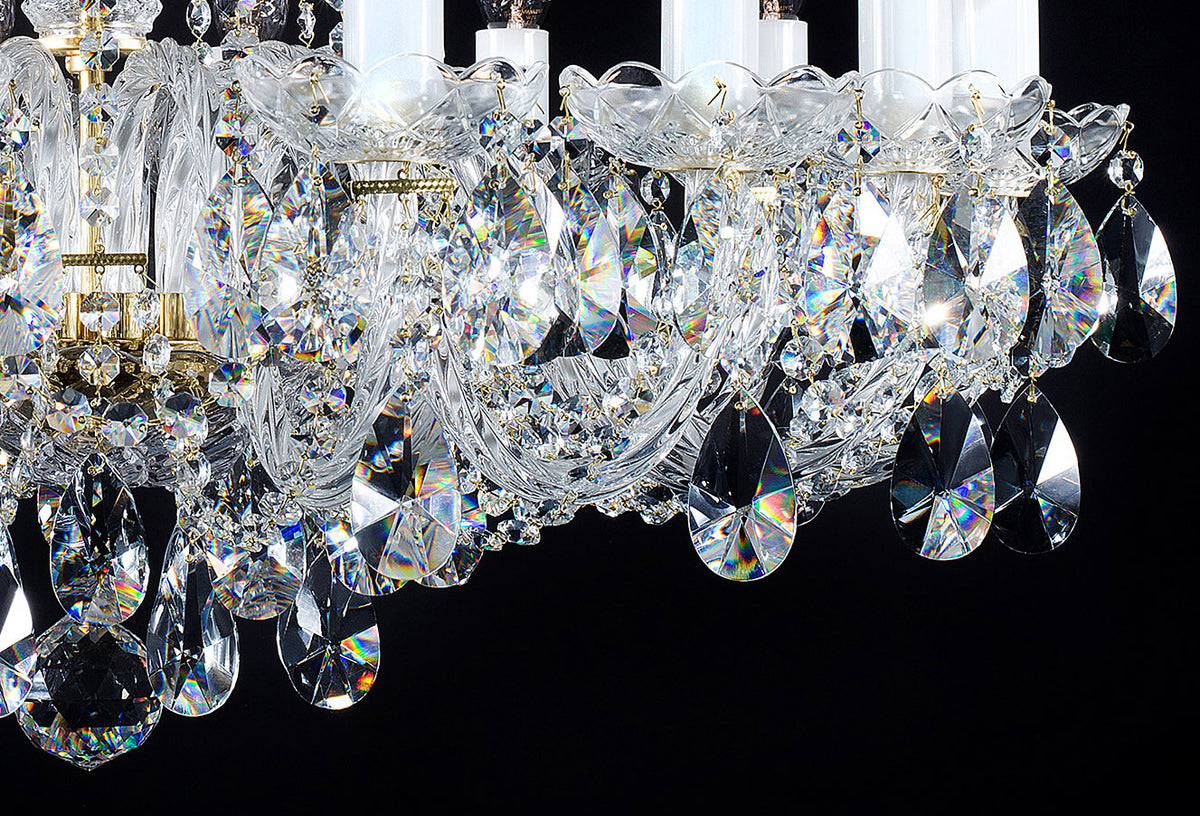 Détail des pendants de cristal taillés et des bras, avec reflets irisés sur fond noir.