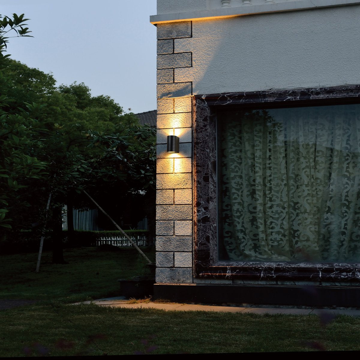 Mise en ambiance nocturne sur un mur extérieur en pierre, éclairant le jardin