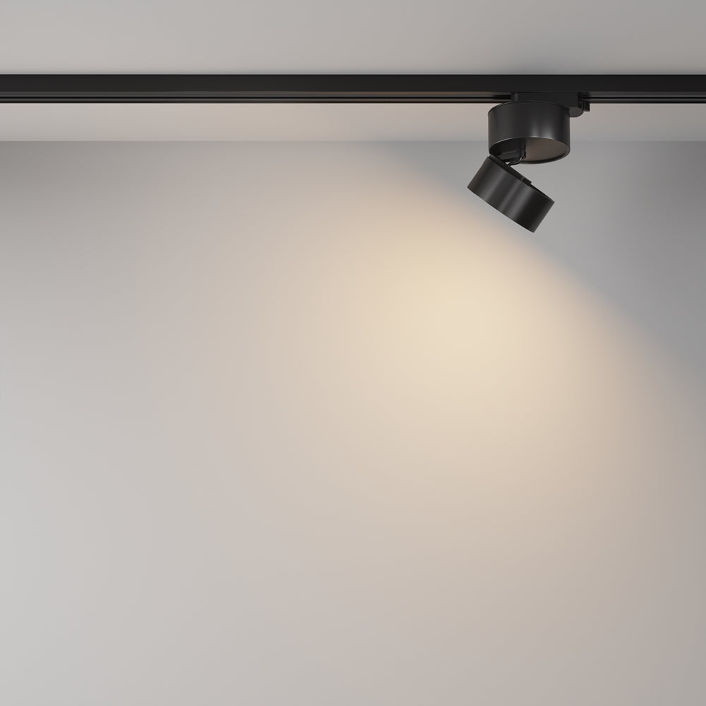 Spot incliné projetant un halo lumineux chaud sur un mur blanc