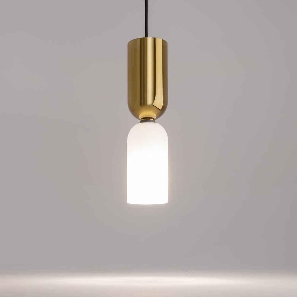 Gros plan du luminaire allumé, laiton poli et verre dépoli diffusant une lumière chaude