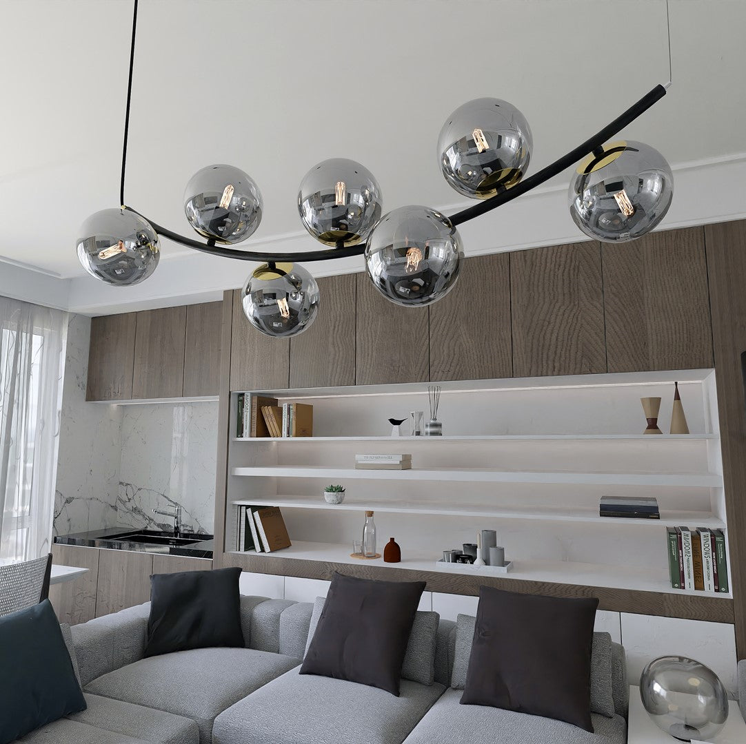 Vue plongeante dans le séjour, suspension allumée au-dessus du coin salon et cuisine.