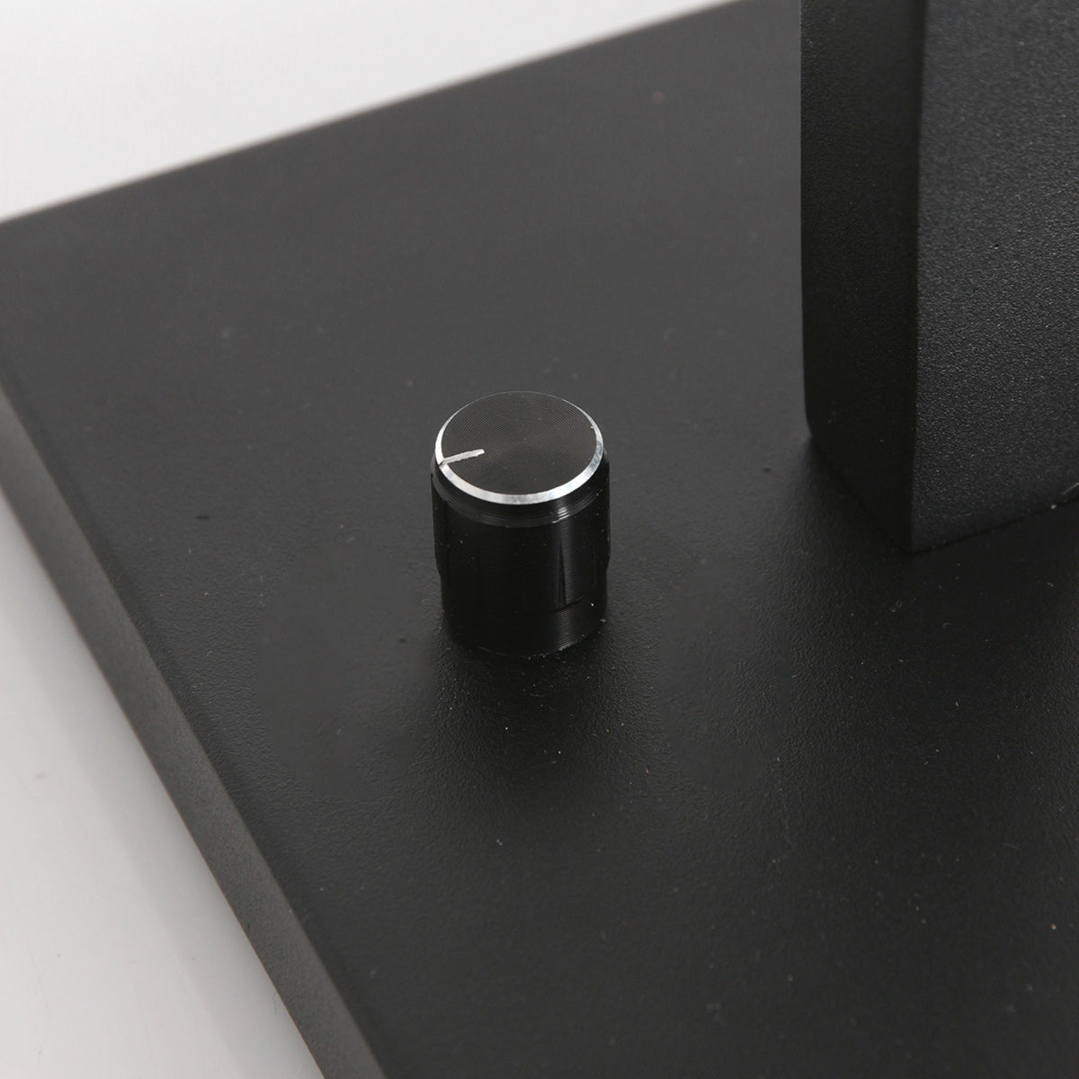 Détail du socle noir avec interrupteur rotatif cranté et repère blanc.
