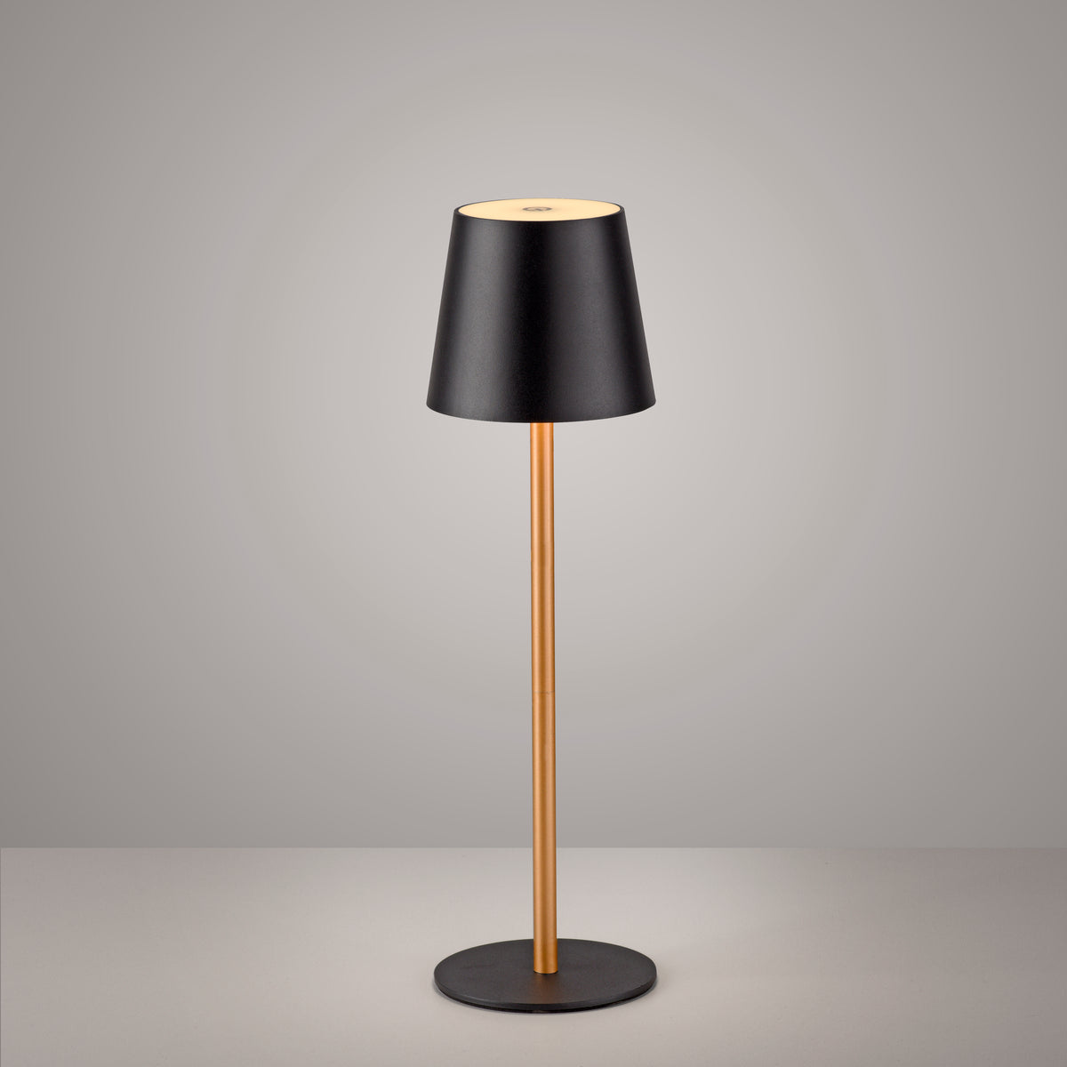 Vue de face de la lampe noire et laiton sur fond gris dégradé clair.