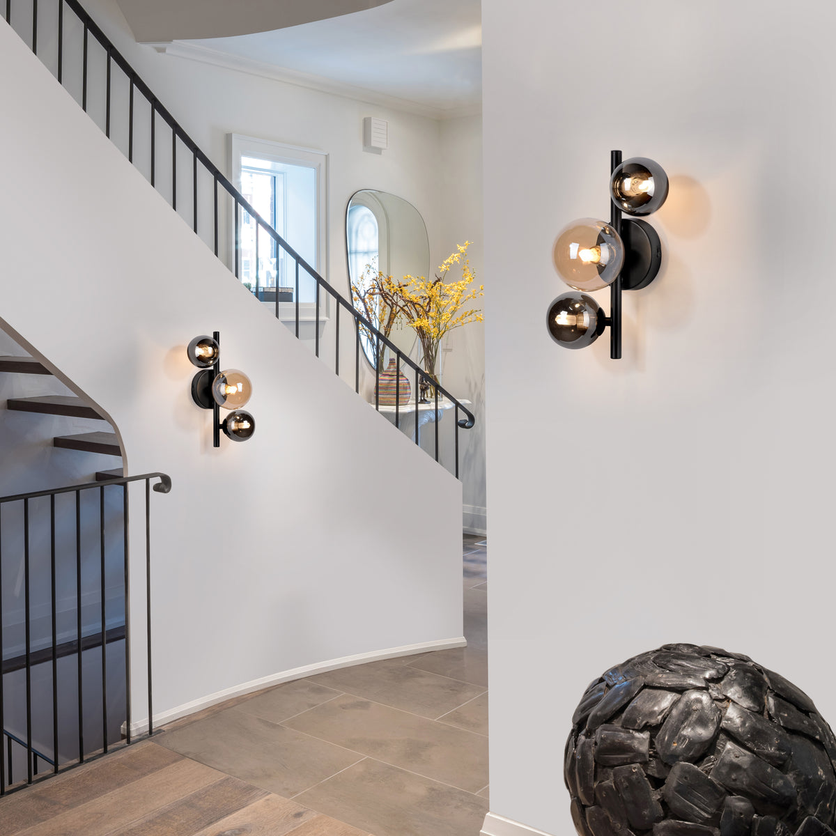 Mise en ambiance dans une entrée avec escalier, deux appliques murales allumées