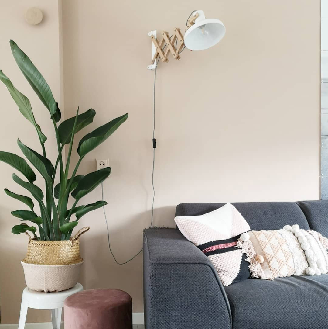 Lampe murale articulée en bois Woody installée au-dessus d'un canapé dans un salon