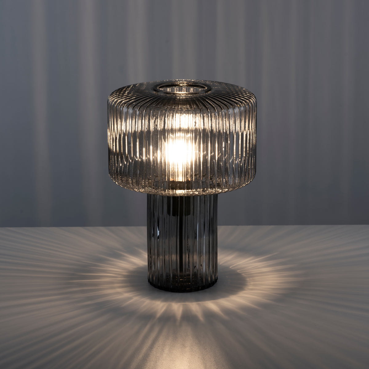 Lampe allumée dans une pièce sombre, projetant un halo lumineux radial sur la table.
