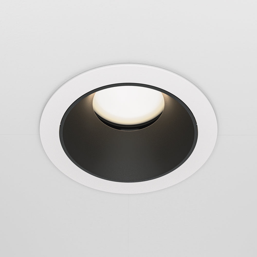 Vue de face légèrement décalée du spot encastré, halo lumineux doux.