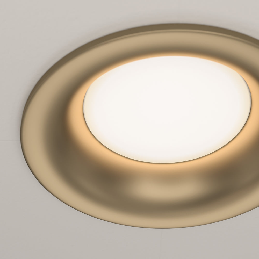 Détail de la collerette dorée mate et du halo lumineux chaud du diffuseur