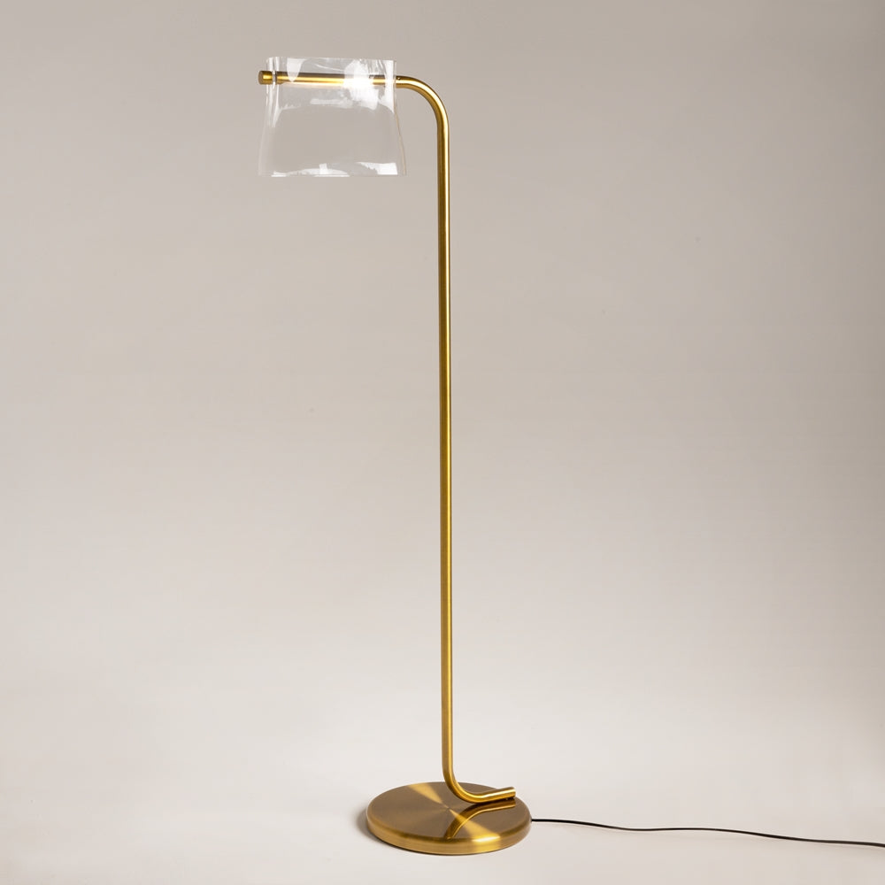 Lampadaire doré éteint, tige recourbée et base ronde sur fond beige