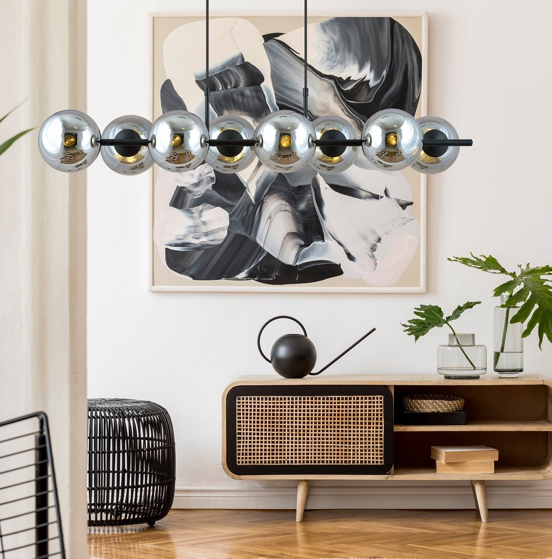 Luminaire suspendu devant un grand tableau abstrait noir et blanc, au-dessus d'un meuble en bois