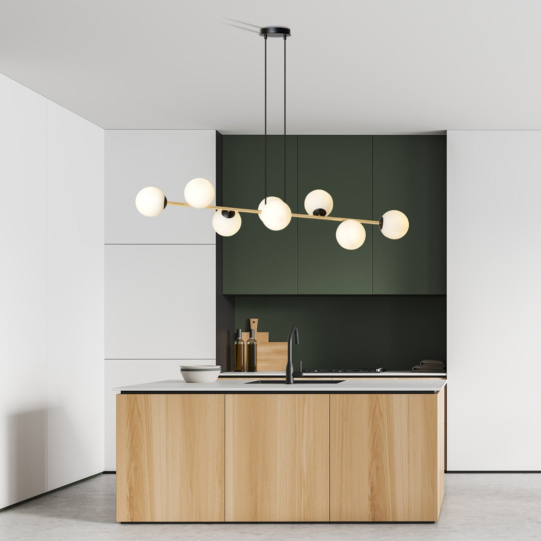 Suspension allumée devant meubles verts et plan de travail, rendu chaleureux dans cuisine moderne.