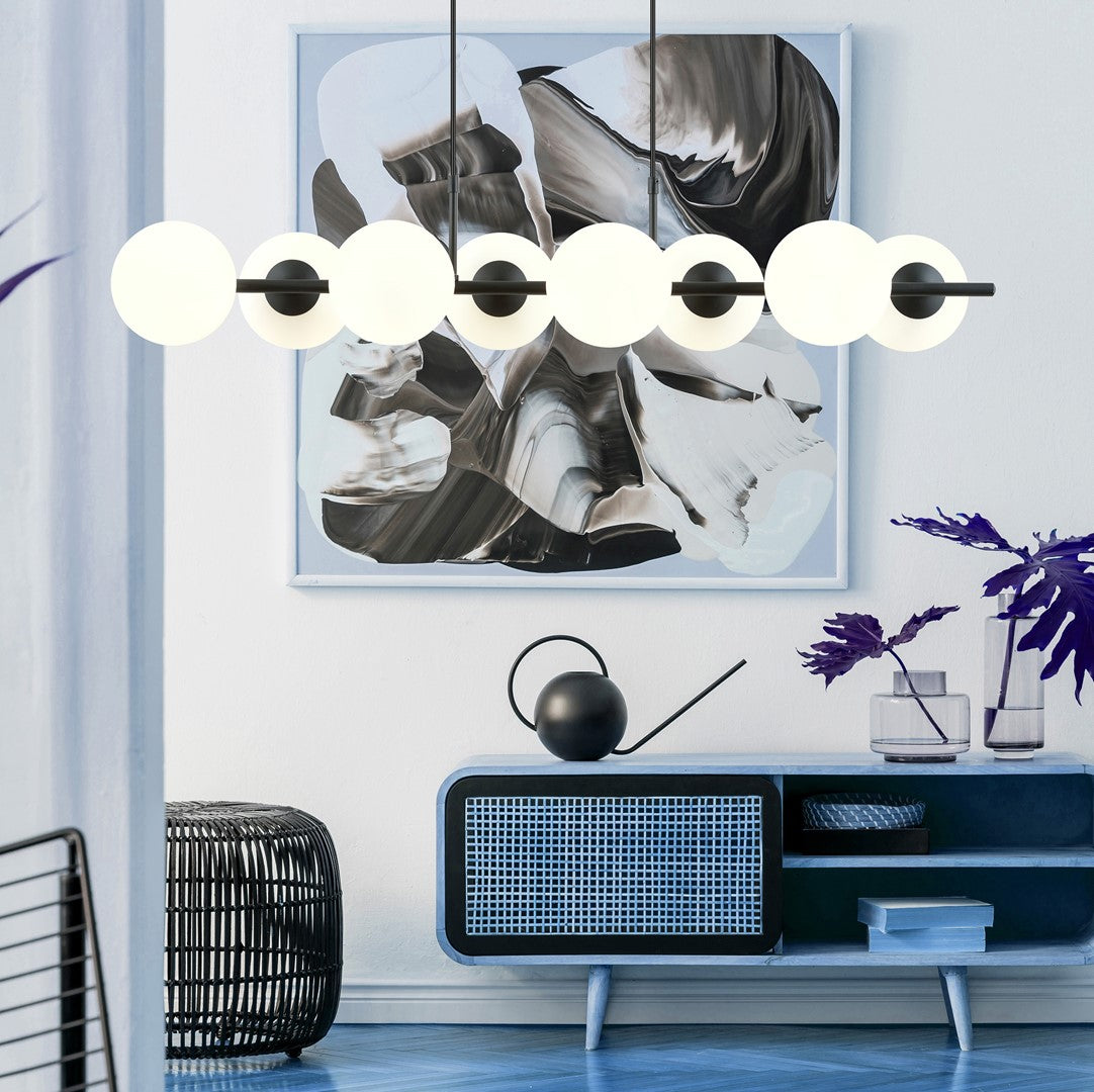 Mise en ambiance au-dessus d'un meuble bleu, luminaire suspendu aux globes opale allumés