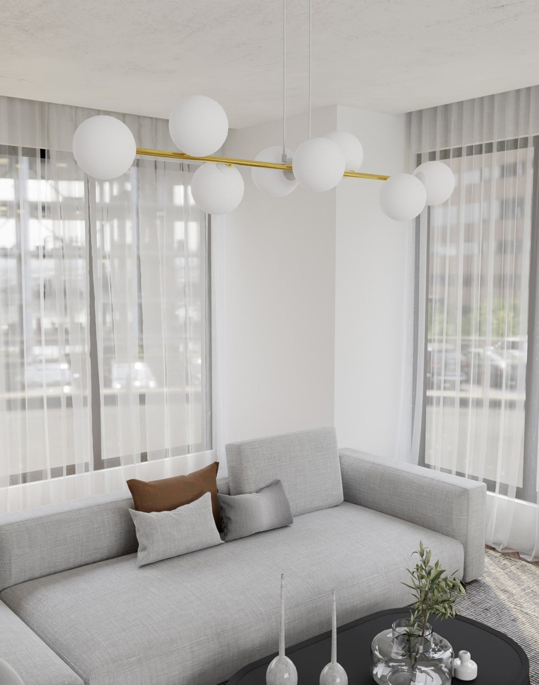 Suspension allumée dans un salon contemporain, au-dessus d'un canapé gris et d'une table basse.