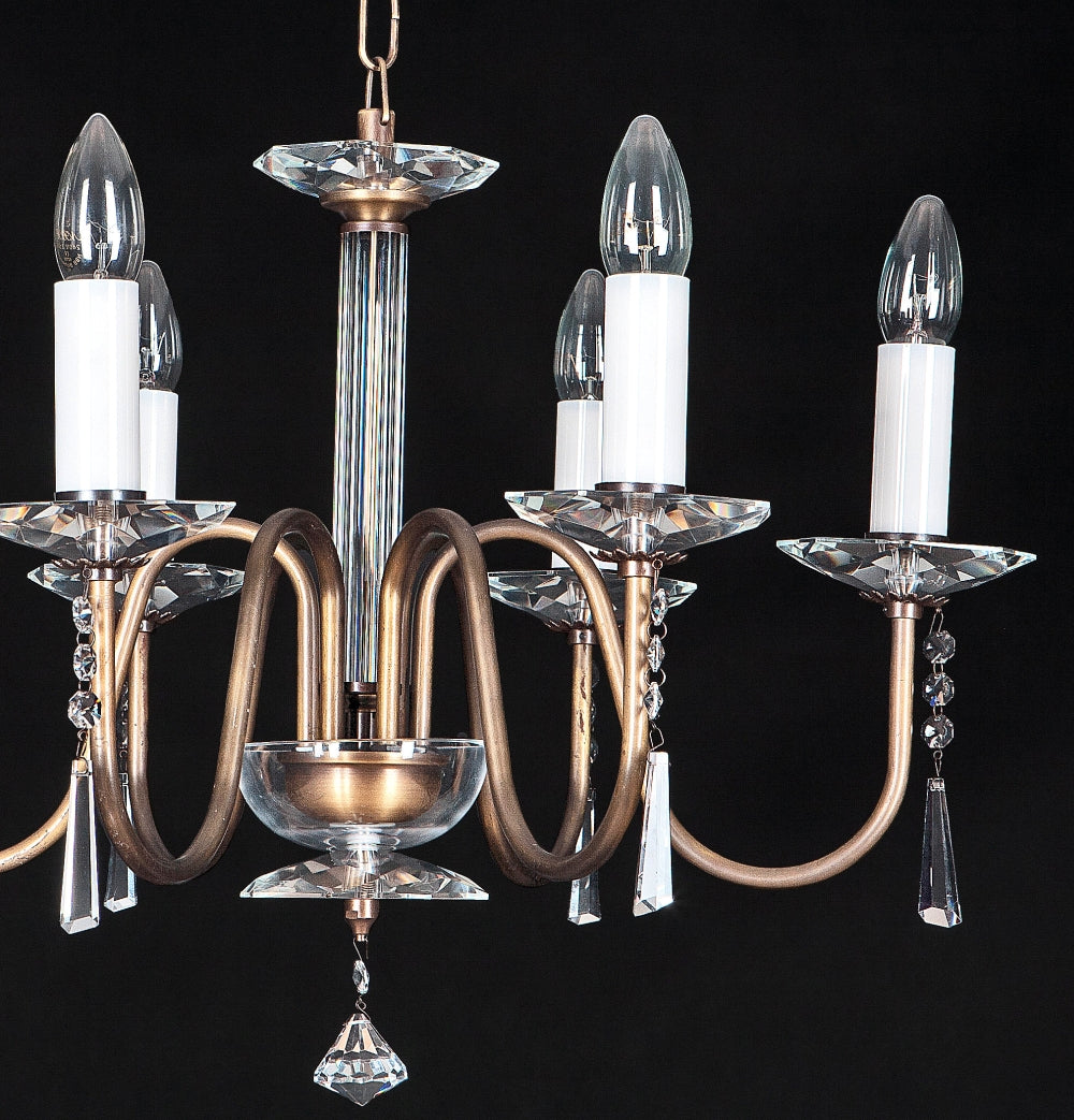 Vue de face du lustre allumé, colonne centrale en cristal et bras recourbés couleur bronze