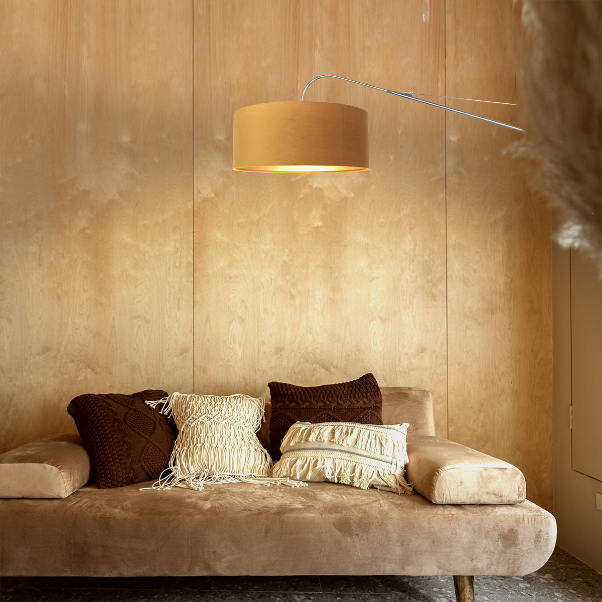 Mise en ambiance chaleureuse : applique murale allumée au-dessus d'un canapé en velours.