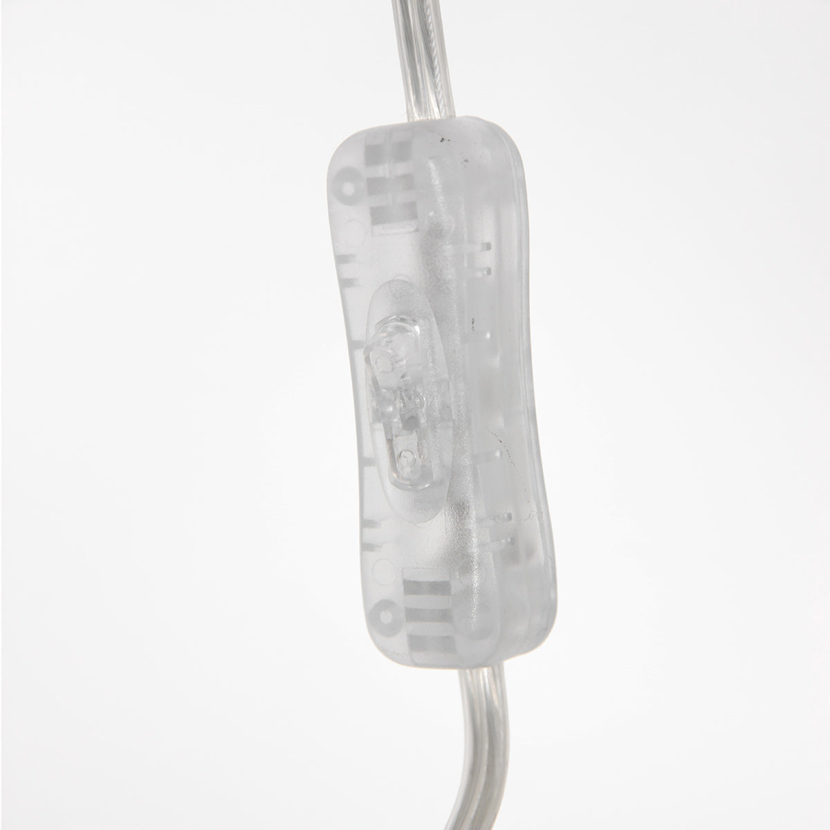Gros plan sur l'interrupteur transparent placé sur le câble électrique de la lampe.