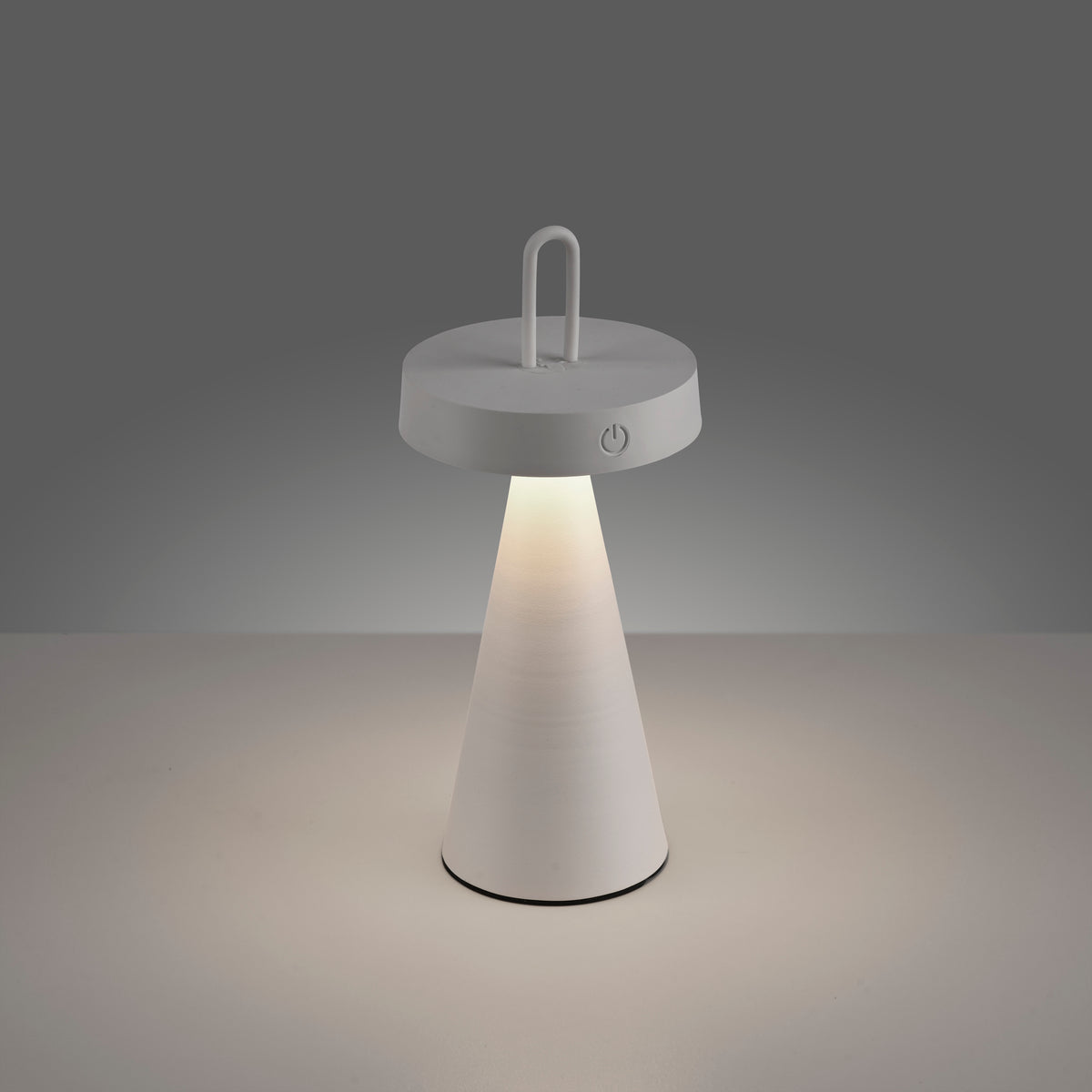Lampe allumée posée sur surface claire, lumière chaude visible.