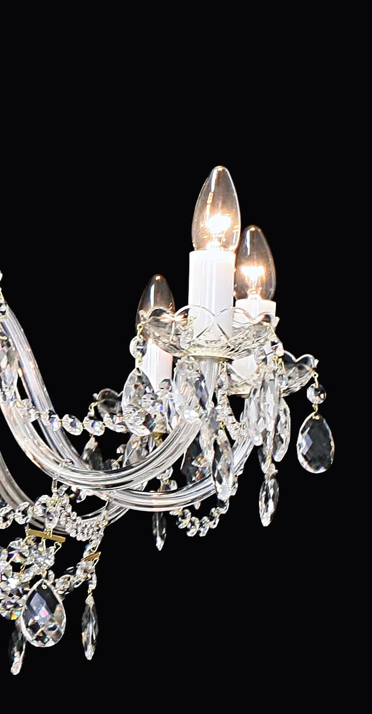 Détail rapproché d'une bobèche, ampoule allumée et pendentifs en cristal taillé.