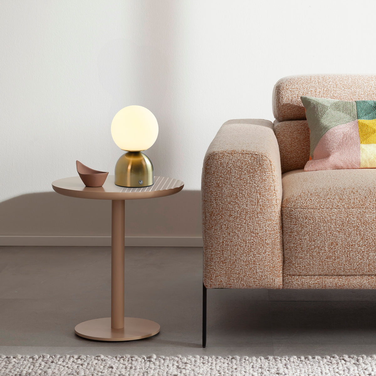 Mise en ambiance sur table d'appoint près d'un canapé beige et coussins colorés.