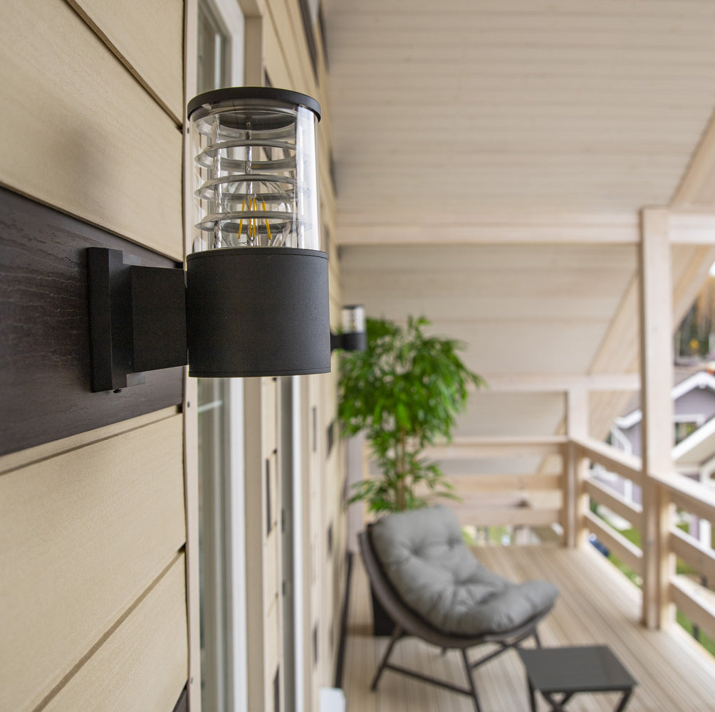 Mise en ambiance sur une terrasse en bois, applique allumée près d'un fauteuil