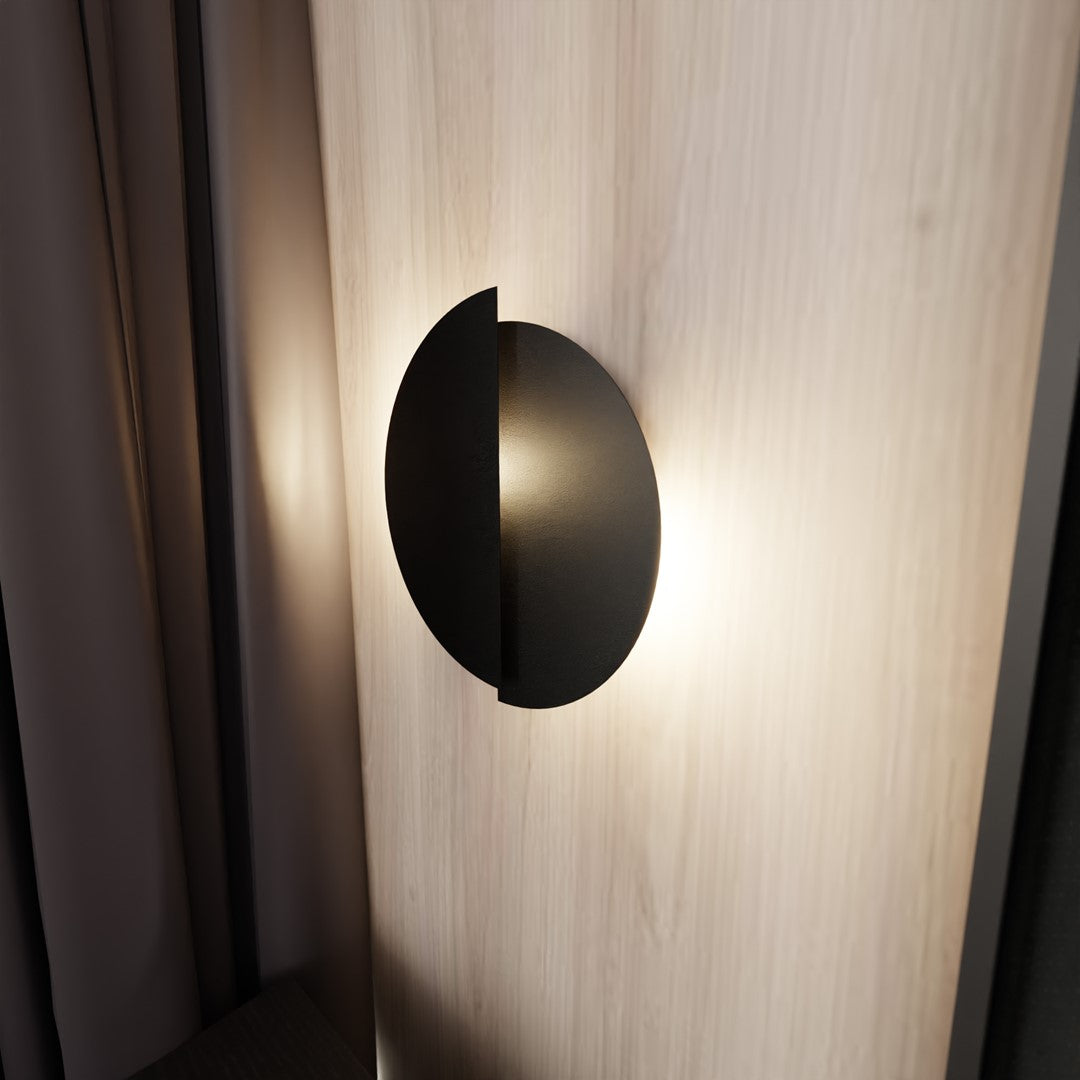 Applique allumée sur mur de bois clair, halo lumineux diffus vers le bas