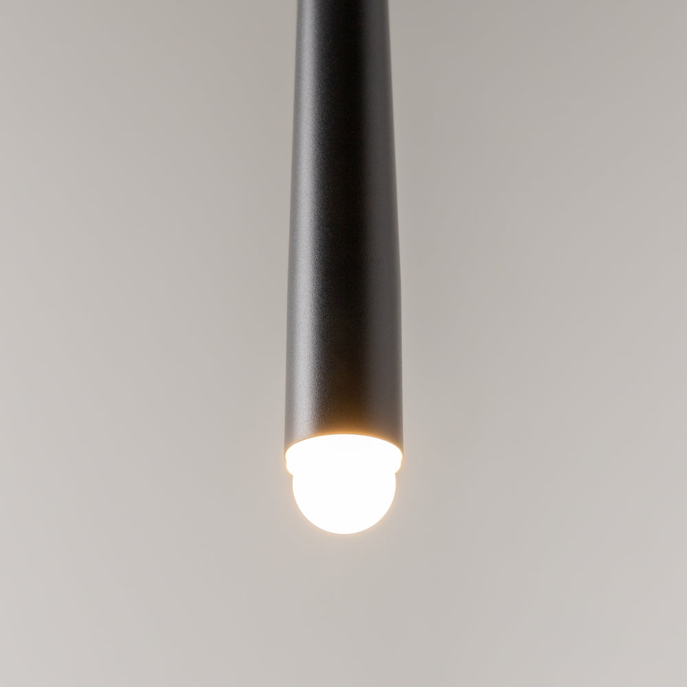 Gros plan sur l'extrémité lumineuse du tube noir, LED diffusant une lueur blanc chaud.