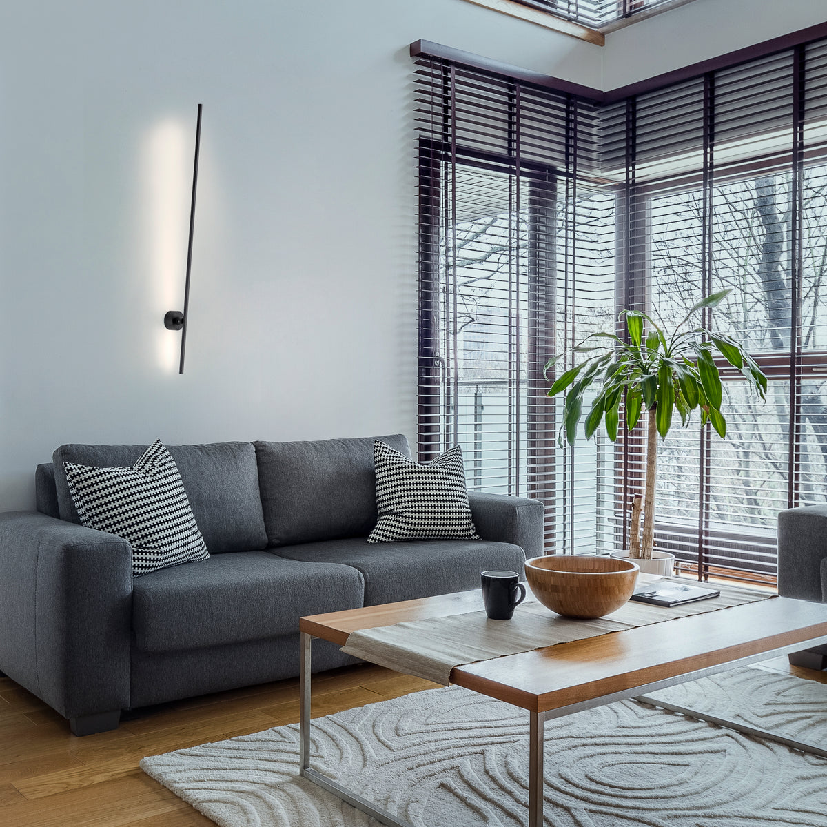 Mise en ambiance dans un salon gris, applique allumée au-dessus du canapé
