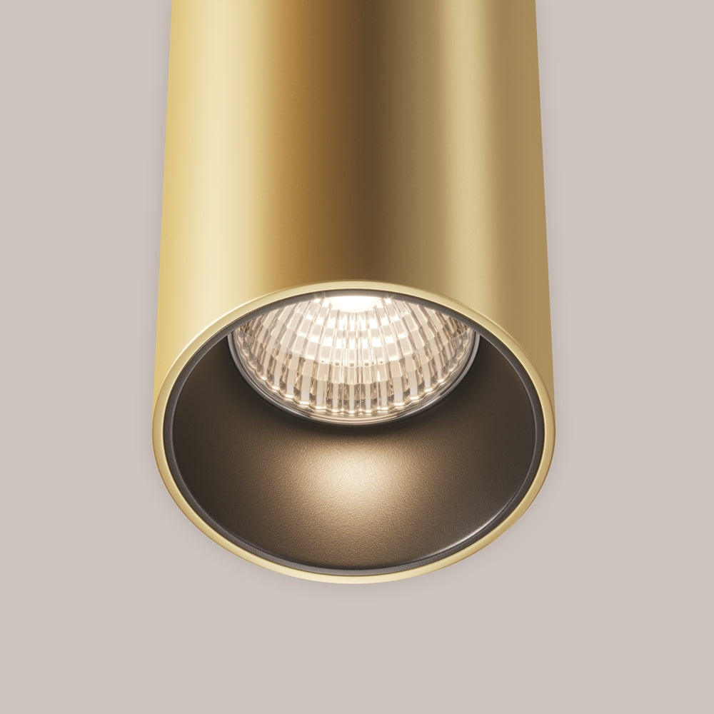 Détail rapproché de la source LED dans le cylindre doré, réflecteur facetté.