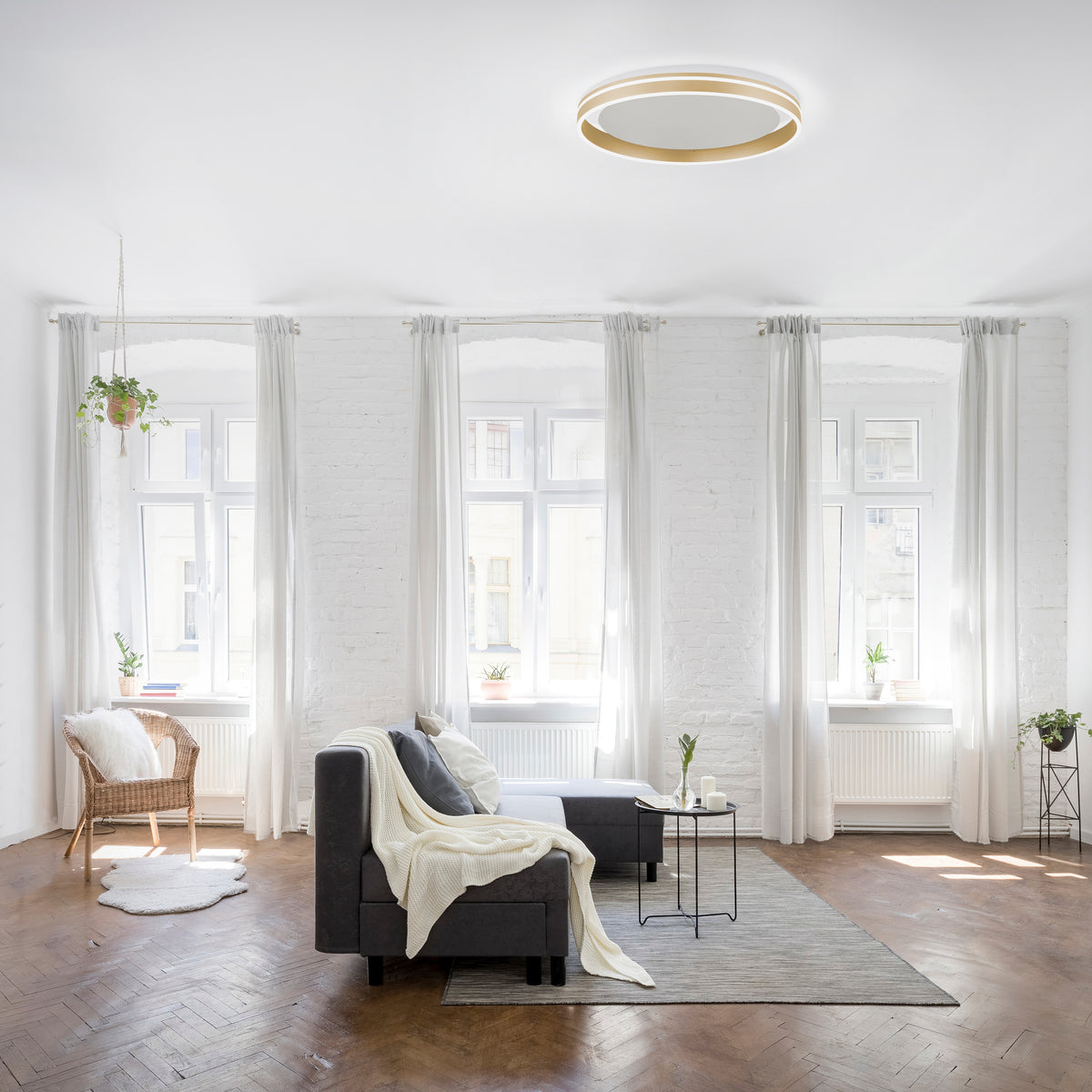 Mise en ambiance du plafonnier dans un salon blanc lumineux, vue depuis le sol.