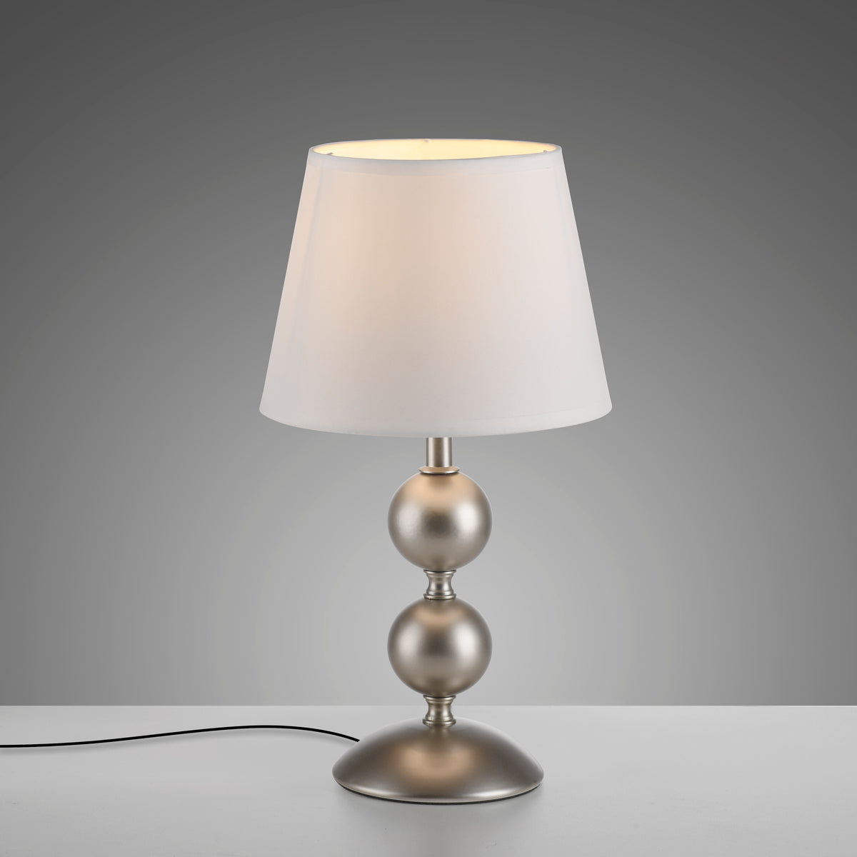 Luminaire allumé sur fond gris dégradé, câble d'alimentation noir visible à gauche