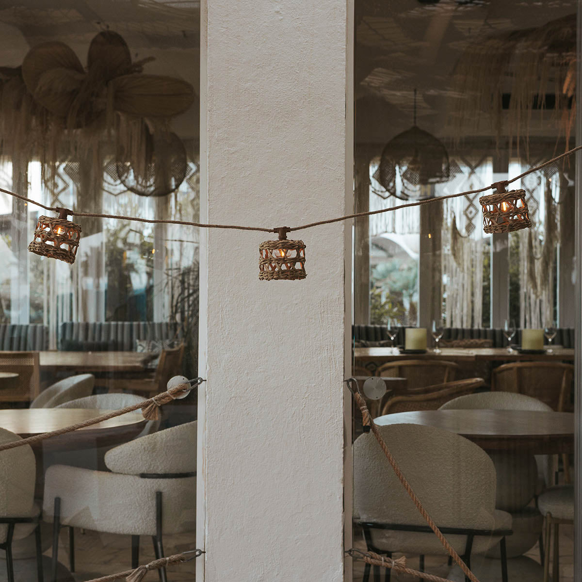 Guirlande tendue devant la vitrine d'un restaurant, trois lanternes tressées visibles