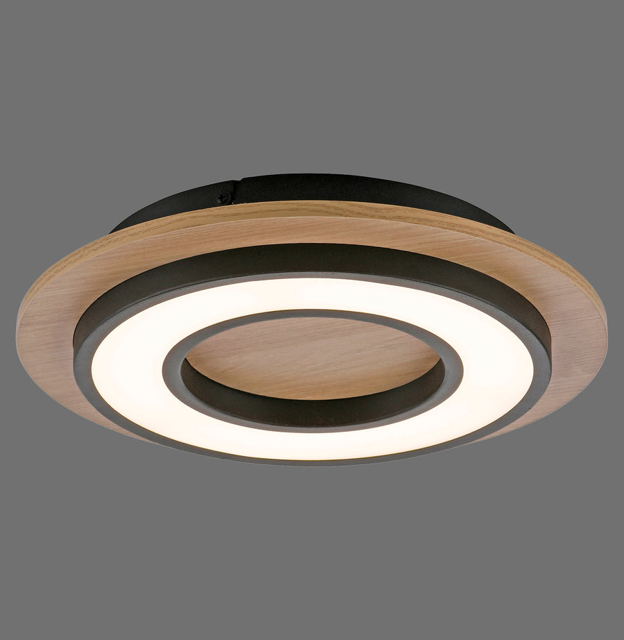 Plafonnier rond en bois clair et noir, anneau LED allumé, vue de trois quarts