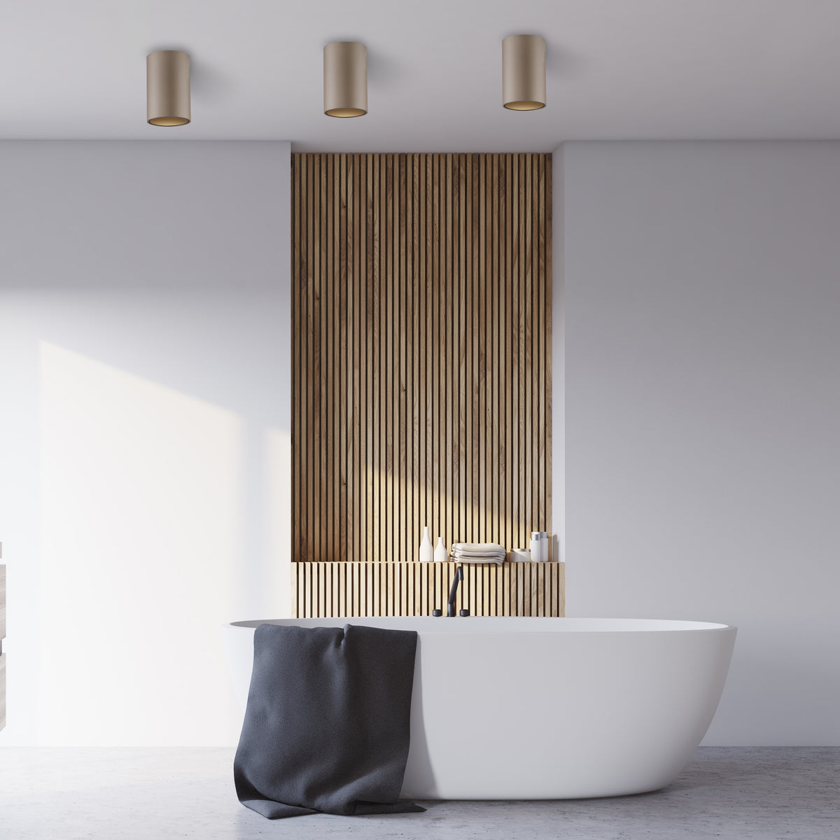 Ambiance salle de bain, trois plafonniers bronze au-dessus d'une baignoire îlot blanche