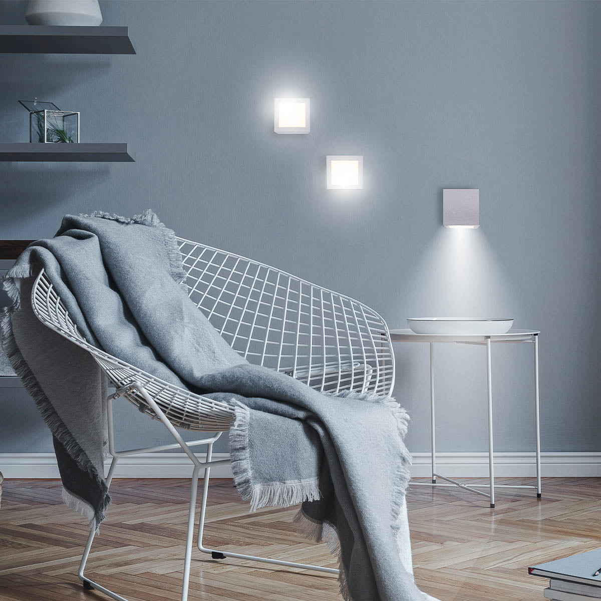Mise en ambiance claire avec appliques carrées blanches allumées près d'un fauteuil