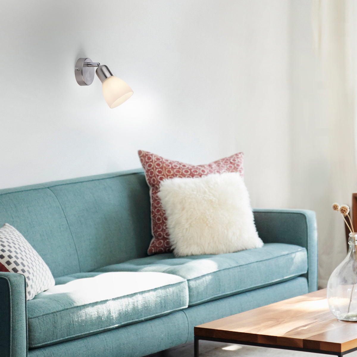 Mise en ambiance salon avec applique murale allumée au-dessus d'un canapé bleu clair.