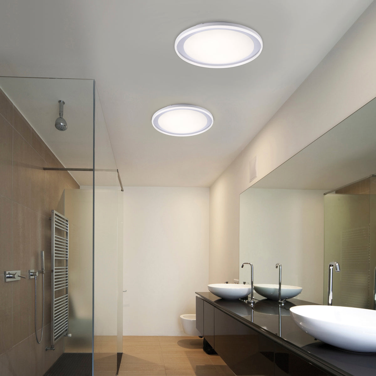 Mise en ambiance dans une salle de bain avec deux plafonniers ronds allumés au plafond.