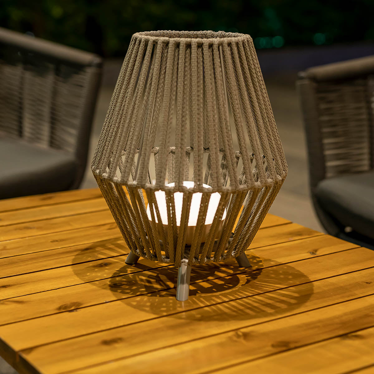Lampe allumée sur table en bois, ombres portées des cordes