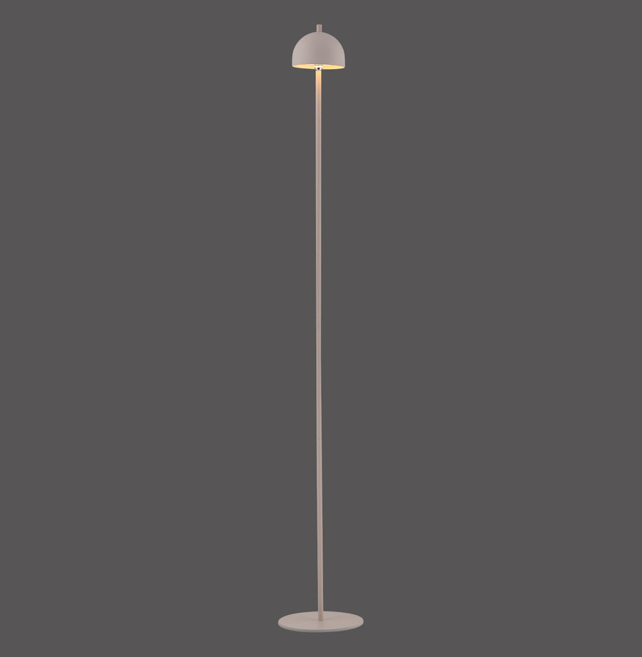 Lampadaire beige de face sur fond gris, abat-jour dôme et long pied fin.