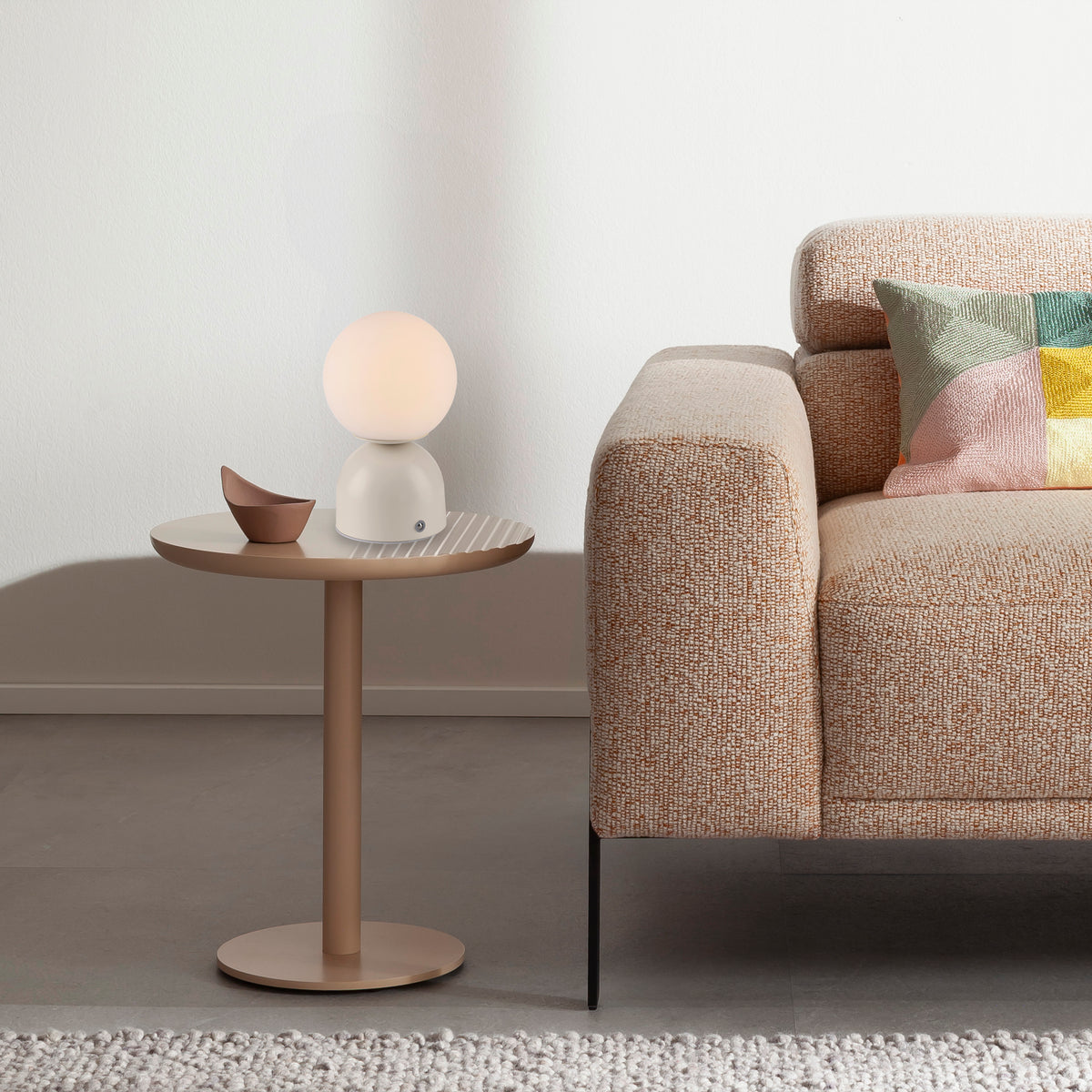 Mise en ambiance sur table d'appoint près d'un canapé beige et coussins colorés.