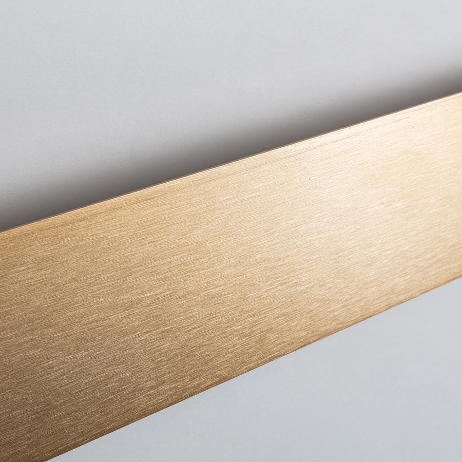 Gros plan de la surface dorée brossée avec reflets et texture fine