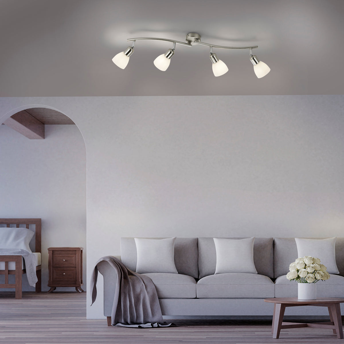Mise en ambiance dans un salon avec le plafonnier allumé au-dessus d'un canapé gris.