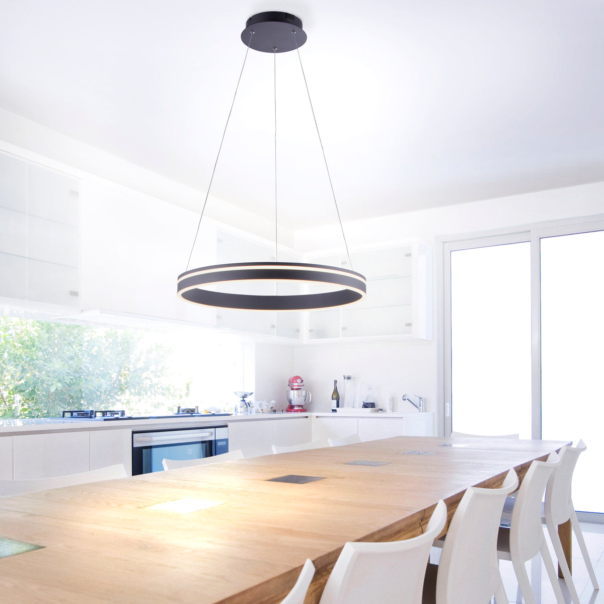 Mise en ambiance au-dessus d'une table de cuisine moderne, suspension ronde allumée.