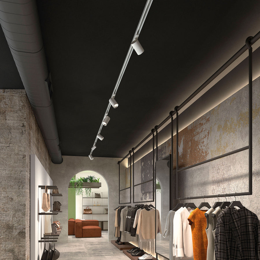 Vue large d’un magasin avec rail de spots blancs au plafond noir.
