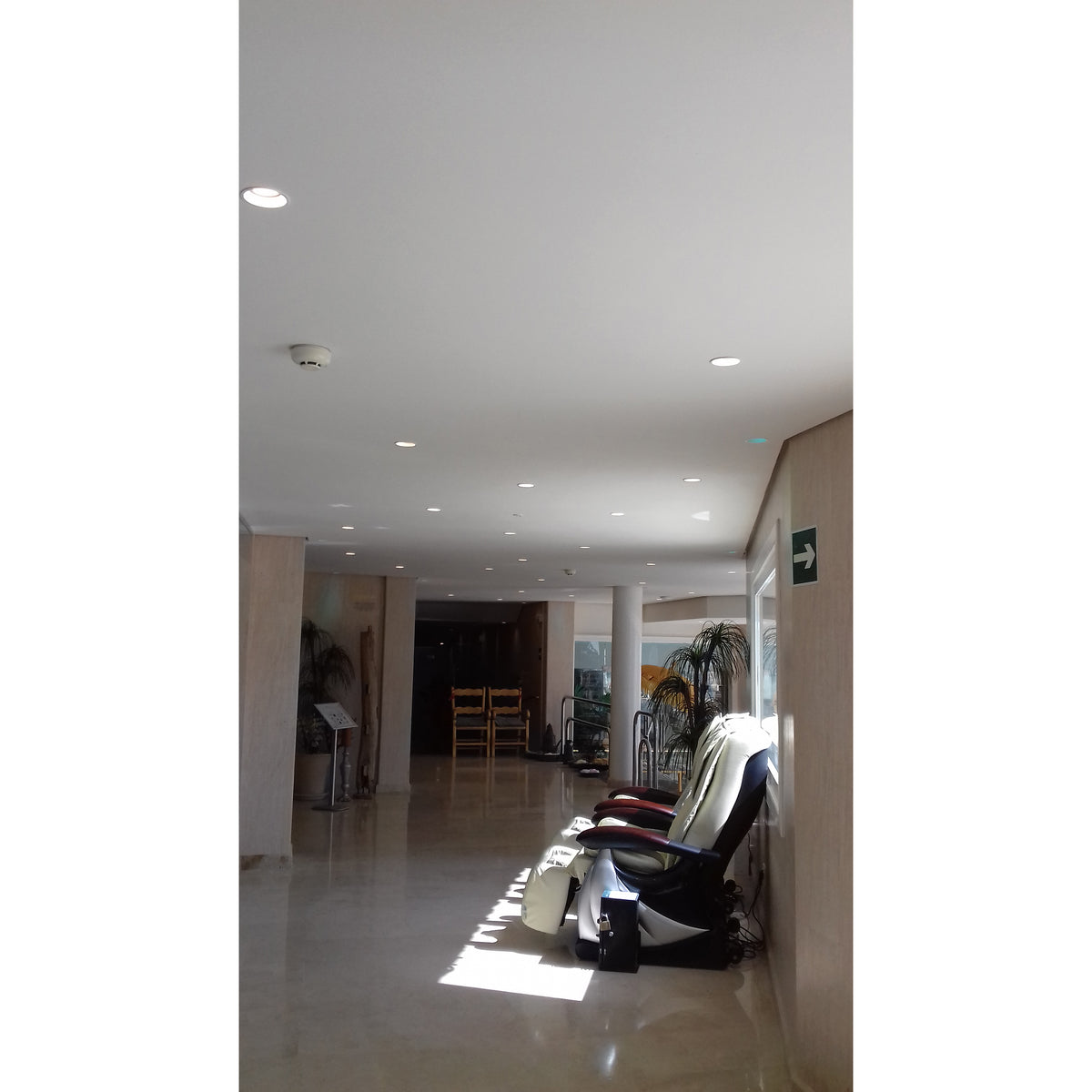 Couloir clair avec plafond ponctué de spots encastrés ronds allumés et non allumés.