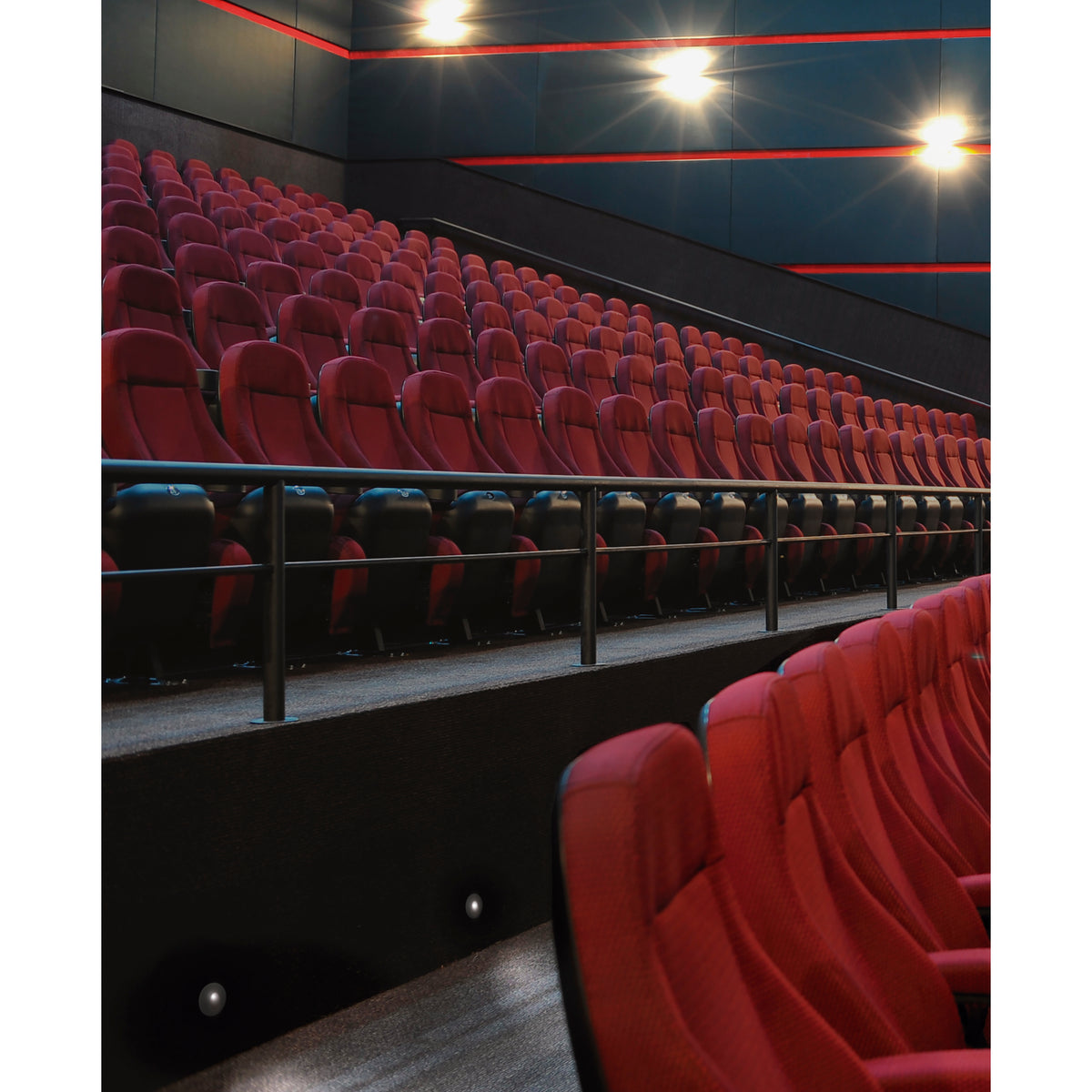 Mise en ambiance dans une salle de cinéma, spots encastrés éclairant marches et allées.