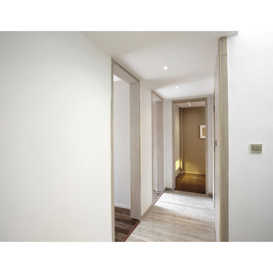 Couloir lumineux avec plusieurs spots encastrés au plafond, rendu discret et moderne.