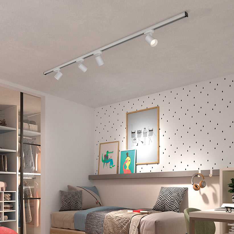 Chambre d’enfant aménagée avec quatre spots blancs orientables sur un rail au plafond.